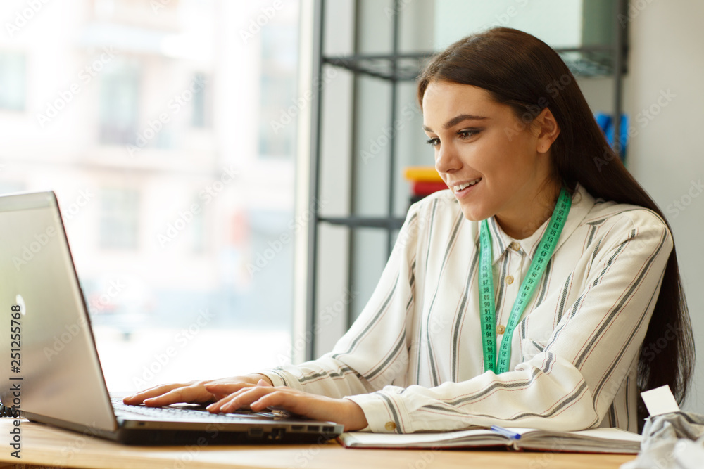 Portrait of successful girl typing text on laptop, focusing on computer screen.