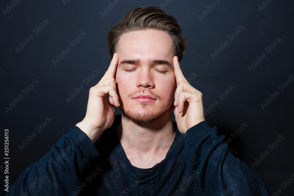 A young man with a headache holding head, isolated on gray background A young man with a headache holding head, isolated on gray background