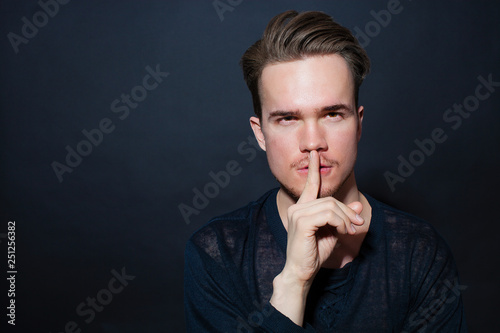 Young man showing silence gesture
