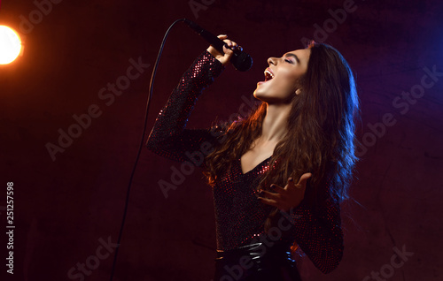 Beautiful singing girl curly afro hair. Beauty woman singer sing with microphone karaoke song on stage smoke, spotlights