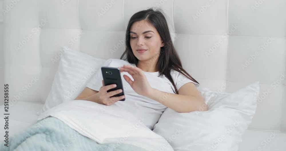 Pretty girl using smartphone early morning in the bed Pretty girl using smartphone early morning in the bed