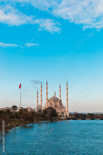Sabanci Central Mosque in Adana with Seyhan River and Trees. Mosque has reflections from Seyhan river in sunny day with blue clean sky