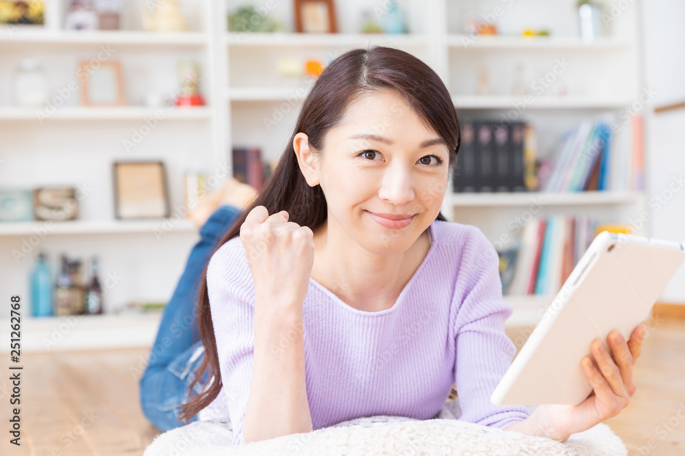 部屋でタブレットコンピューターを見る女性 部屋でタブレットコンピューターを見る女性
