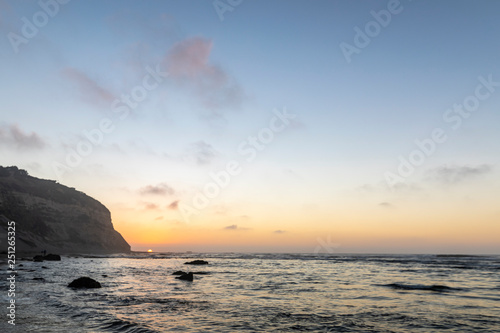 Amazing Las Brisas beach an awe sea coastline landscape on a wild environment in Chile. The sun goes down over the infinite horizon behind the cliffs reflected on the sea water with orange tones