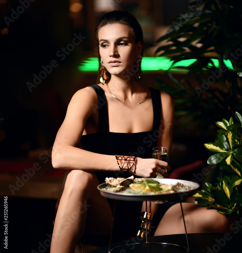 Beautiful sexy fashion brunette woman in expensive interior restaurant eat oyster waiting