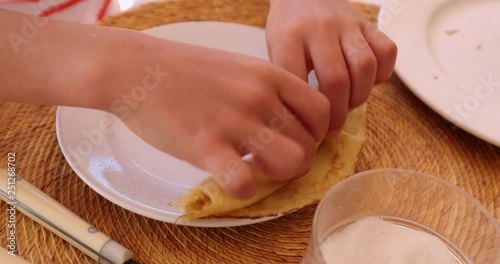 Kid hands rolling a crepe for breakfast photo