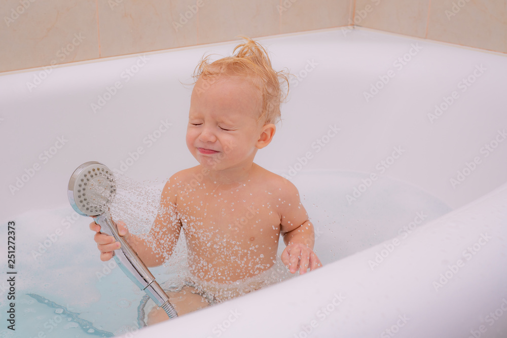 Happy little boy in bath. Little boy in bathtub with fluffy soap bubble