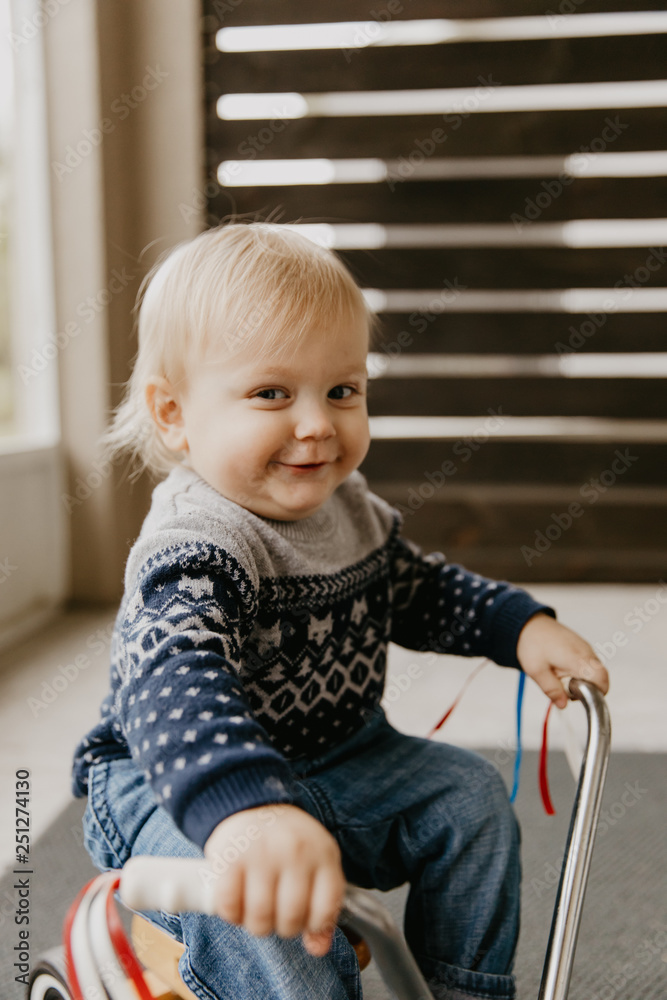 Precious Adorable Cute Little Blonde Baby Toddler Boy Kid Playing Outside on Wooden Toy Bicycle Scooter Mobile Smiling at the Camera and Having Fun