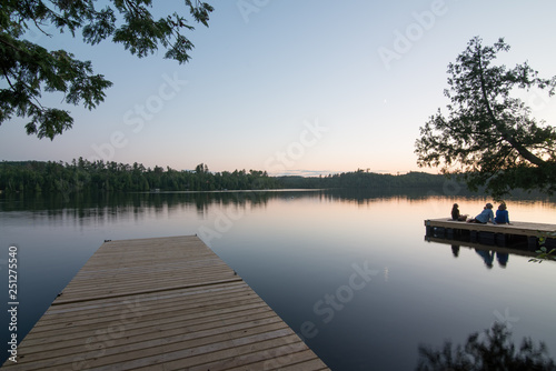 Beautiful sunset taken off a dock on Hungry Jack Lake off the Gunflint Trail in Northern Minnesota with group of people on a dock (no faces visible)