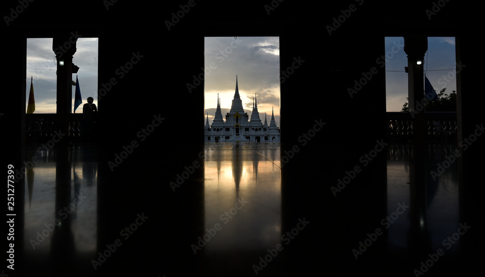 A white Buddhist temple view from a door in an evening
