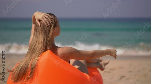 Superslowmotion shot of a young woman relaxing on an inflateble sofa on a tropical beach photo