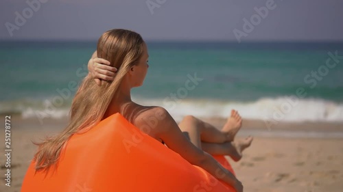 Superslowmotion shot of a young woman relaxing on an inflateble sofa on a tropical beach photo