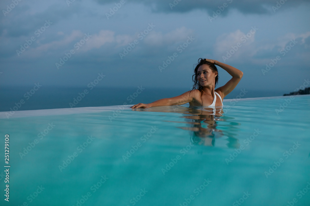 Woman relaxing in swimming pool in evening on summer vacation