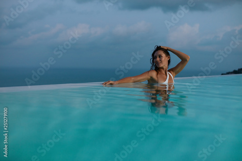 Woman relaxing in swimming pool in evening on summer vacation