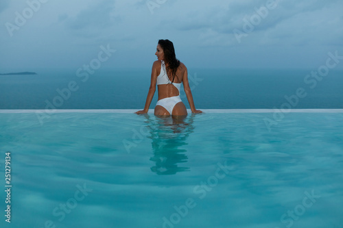 Summer vacation. Woman in swimsuit in infinity swimming pool
