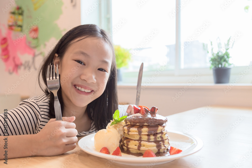 Asian girl is smiling happily,holding a knife and fork is preparing to eat pancakes in restaurants Asian girl is smiling happily,holding a knife and fork is preparing to eat pancakes in restaurants