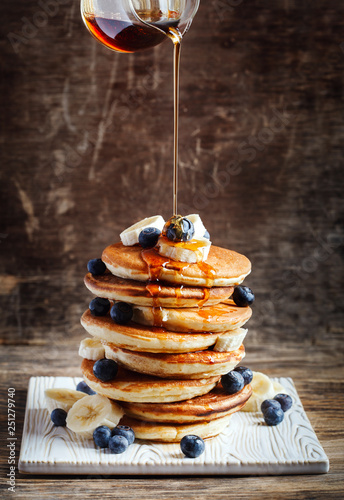 Pancakes with banana, blueberry and maple syrup for a breakfast.
