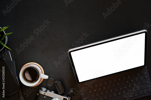 Minimal leather dark desk workspace with tablet, coffee mug, vintage camera and copy space