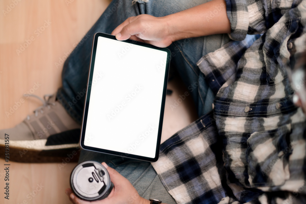 Naklejka premium Top view young man using tablet while sitting on the floor.