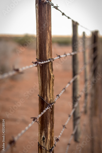 Rusty barb wire fence and old wood poles on Kalahari red sand farm