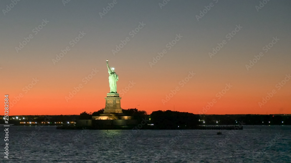 wide angle view of a sunset and the statue of liberty