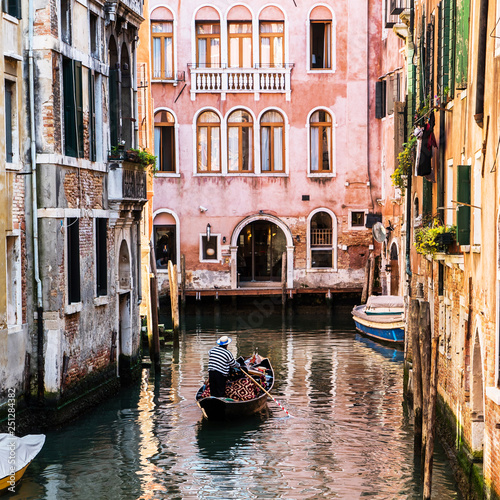 Venetian gondolier punting gondola through green canal waters of Venice Italy © Maksim Shebeko