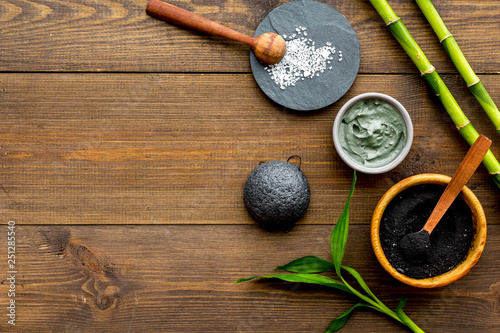 Skin cleansing and detox. Bamboo charcoal powder cosmetics on dark wooden background top view space for text