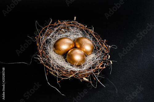 Golden Easter Eggs in birds Nest on black background. Easter Holiday concept abstract background copyspace top view several objects.