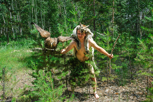 primitive man in the forest hunting with sitting on the arm of an eagle and a lynx skin