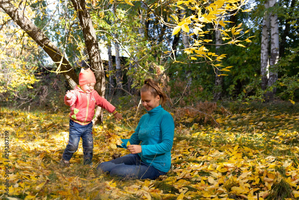 Mom and baby in the park on the background of autumn foliage