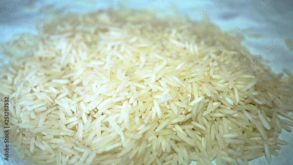 Slow motion white rice pouring onto pile of long grain rice Slow motion white rice pouring onto pile of long grain rice