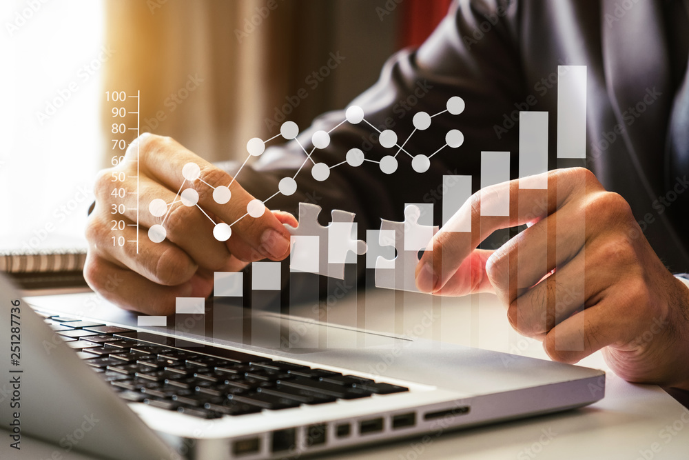 Business solutions and success concept. Businessman hand connecting jigsaw puzzle at office in morning light Business solutions and success concept. Businessman hand connecting jigsaw puzzle at office in morning light