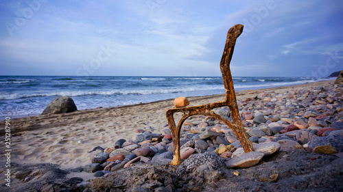 rusty chair on the rocks by the sea