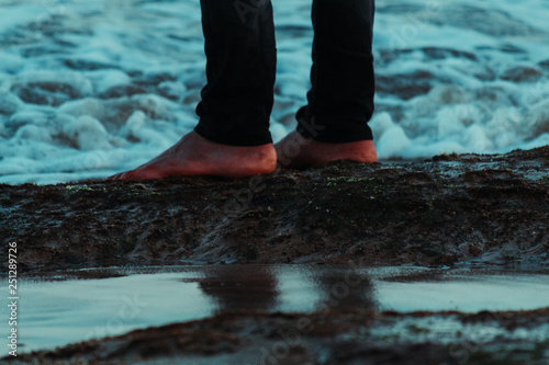 Closeup of legs of person on the beach with sea waves in background