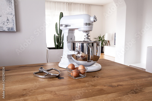 White kitchen machine and stand mixer on a wooden table in a bright design apartment photo