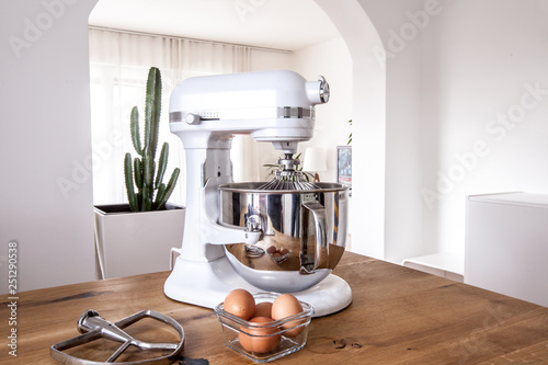 White kitchen machine and stand mixer on a wooden table in a bright design apartment