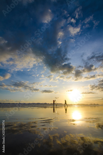 Two guys have an exercise at shore with surfboard while Sunset at Double Six Beach, Legian, Seminyak, Kuta, Bali, Indonesia