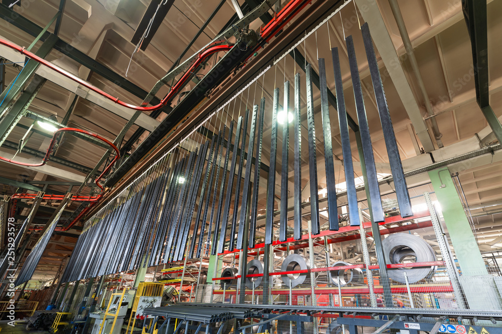 Metal parts are suspended on an overhead conveyor. Line painting in an electrostatic field