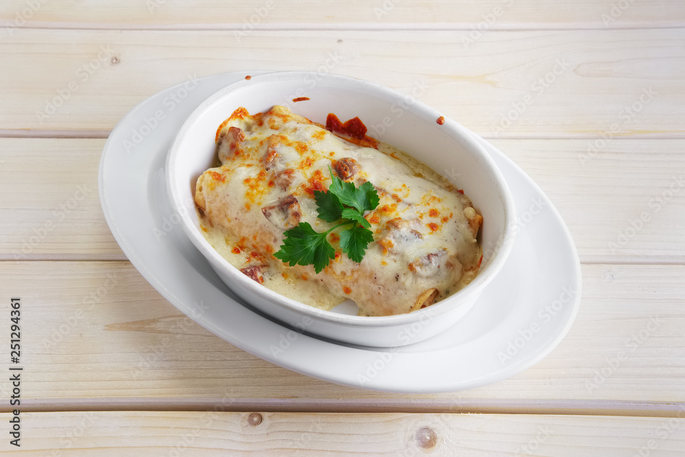Rolled pancakes with ham baked in oven with cheese topping Rolled pancakes with ham baked in oven with cheese topping