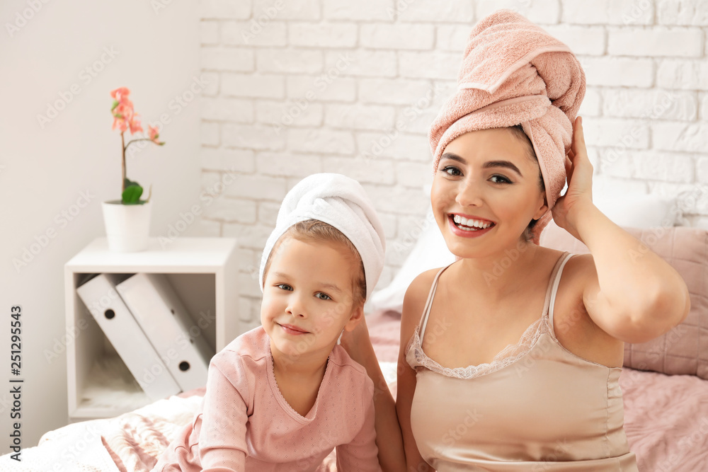 Cute little daughter with her mother after shower sitting on bed Cute little daughter with her mother after shower sitting on bed