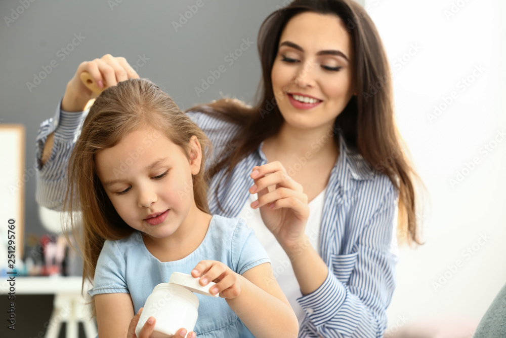 Young mother brushing hair of her cute little daughter at home Young mother brushing hair of her cute little daughter at home