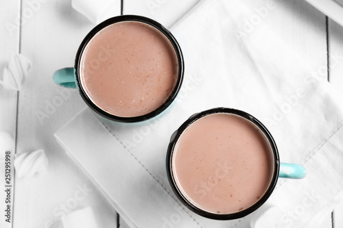 Mugs of hot cacao drink on white table