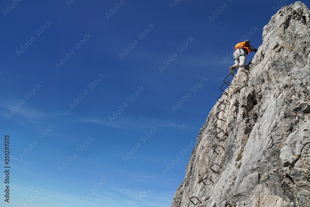 Klettern auf Leiter an Fels am Klettersteig