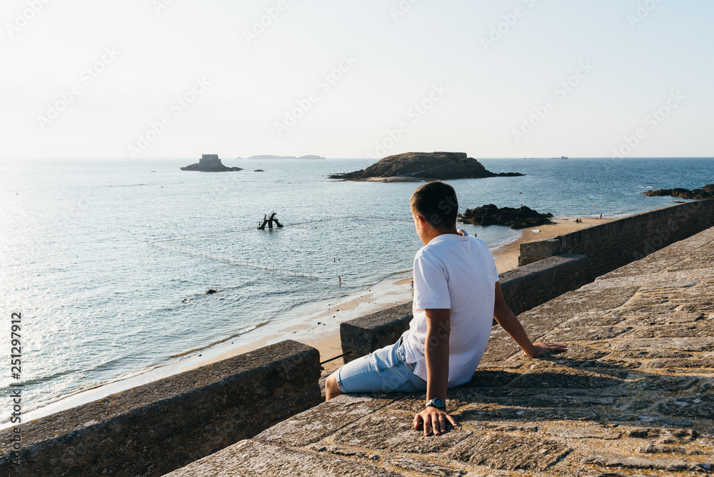 Young man is watching the sunset in the bay of Saint Malo