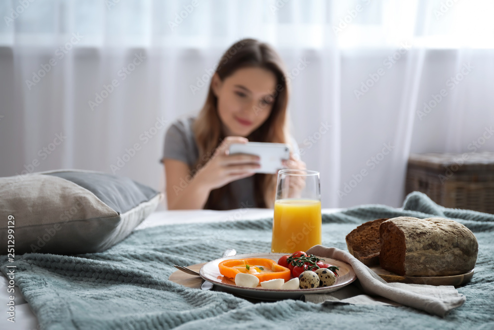 Female food photographer with mobile phone taking picture of tasty breakfast at home
