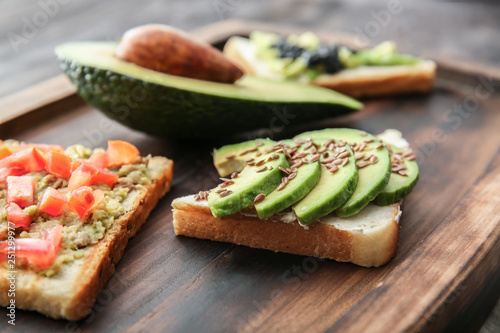 Tasty avocado sandwiches on wooden board, closeup