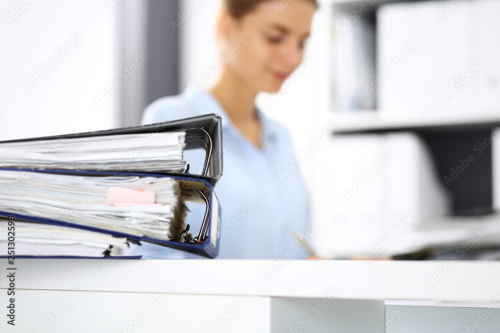 Binders with papers are waiting to be processed by business woman or