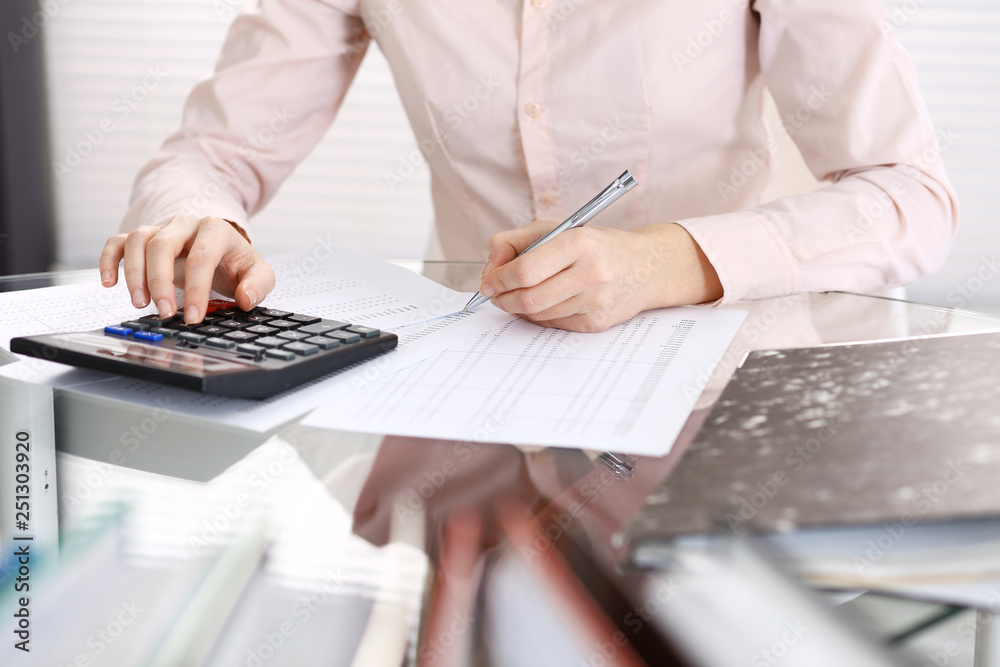 Unknown bookkeeper woman or financial inspector making report, calculating or checking balance, close-up. Business portrait. Audit or tax concepts Unknown bookkeeper woman or financial inspector making report, calculating or checking balance, close-up. Business portrait. Audit or tax concepts