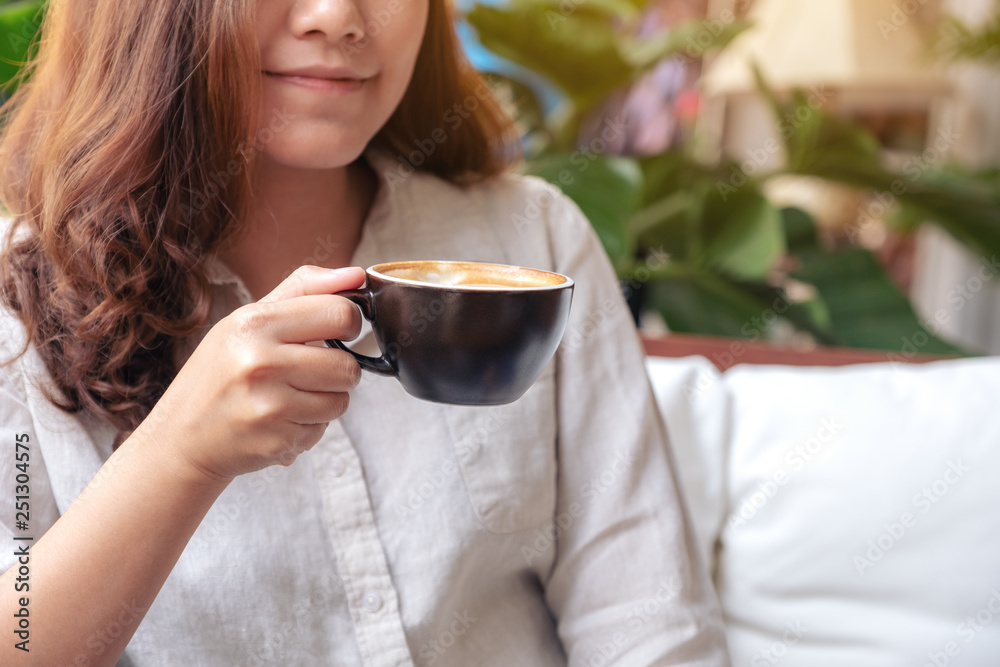 Closeup image of Asian woman smelling and drinking hot coffee with feeling good in cafe Closeup image of Asian woman smelling and drinking hot coffee with feeling good in cafe