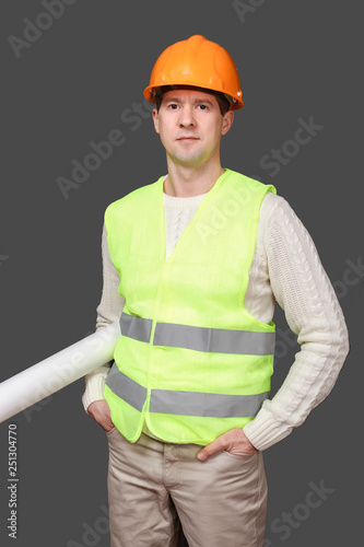 the man the builder in a helmet holds drawings, documents in hand, looks in the camera